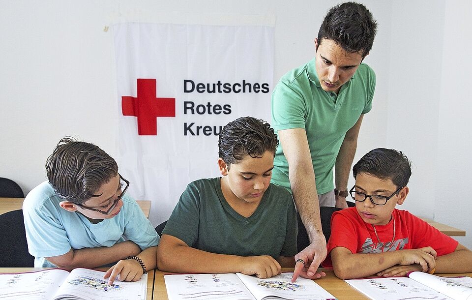 drei Kindern wird etwas vom DRK beigebracht