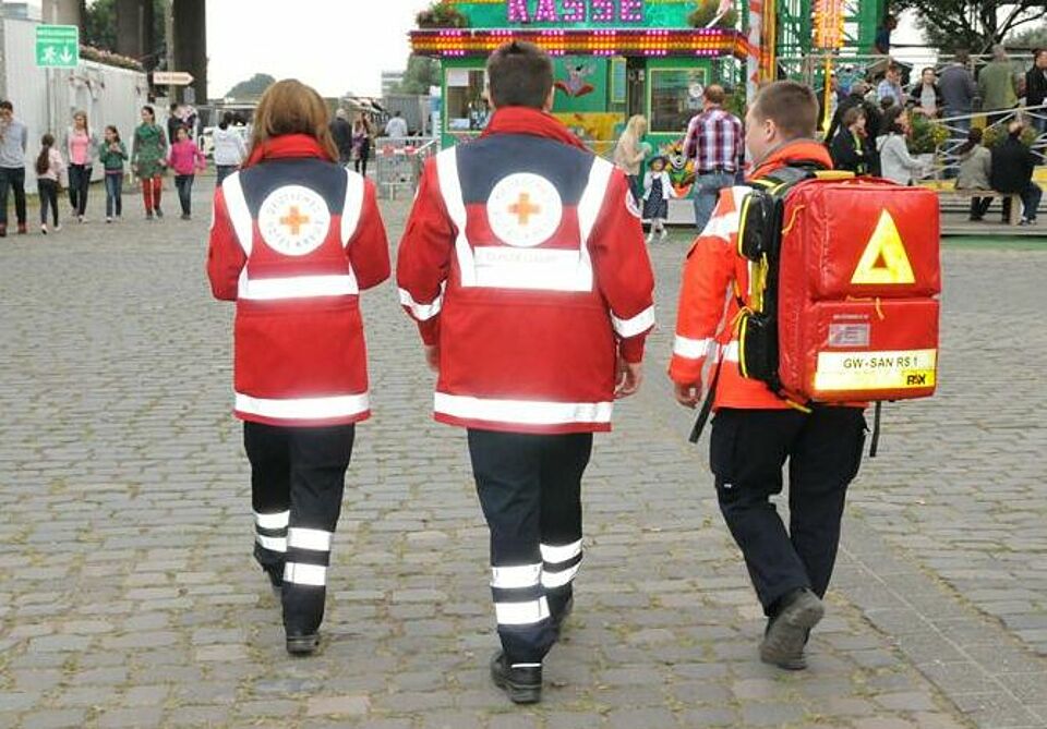 Drei Rettungssanitäter auf Rheinkirmes von hinten fotografiert