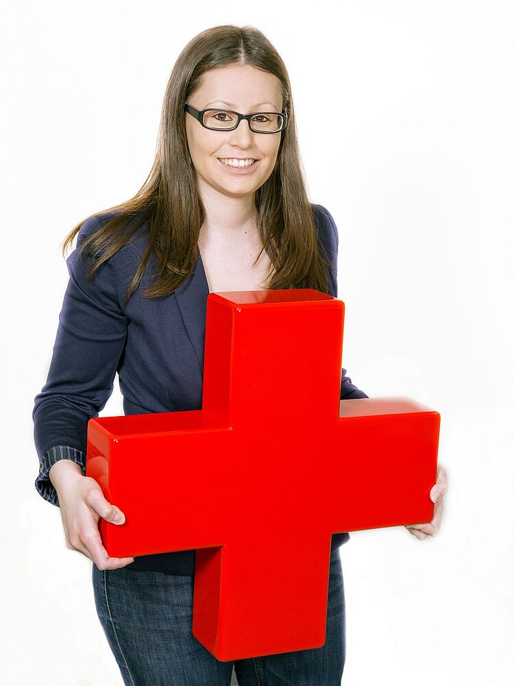 Frau hält großes Rotes Kreuz im Arm