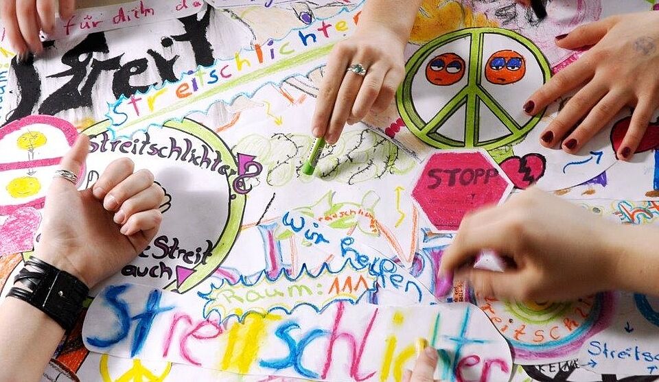 Schulsozialarbeit. Hände malen zusammen ein Bild