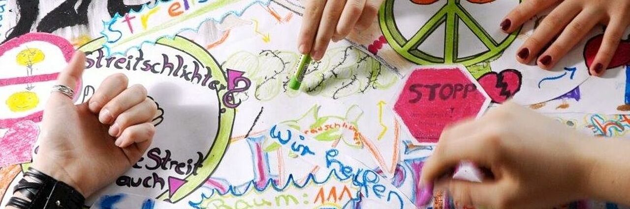 Schulsozialarbeit. Hände malen zusammen ein Bild