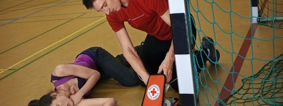 Erste Hilfe Schulung, Ersthelfer sitzt neben bewusstloser Patientin