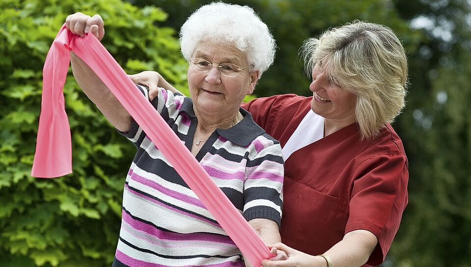 Eine Seniorin wird bei der Gymnastik unterstützt