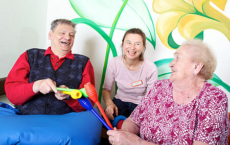 zwei Senioren mit Pflegerin beim musizieren