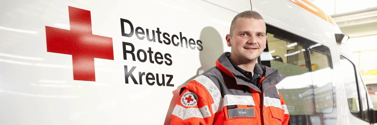 Rettungssanitäter vor DRK Schriftzug an Auto