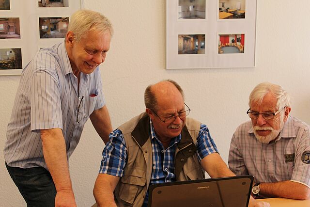 Drei Senioren schauen auf ein LAptop